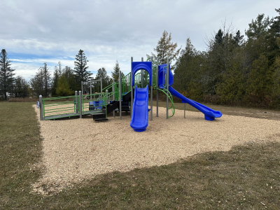 A picture of an accessible playground featuring a slide, swings and several interactive elements.