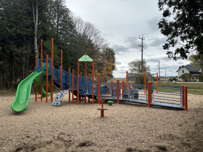 A picture of an accessible playground featuring a slide, swings and several interactive elements.